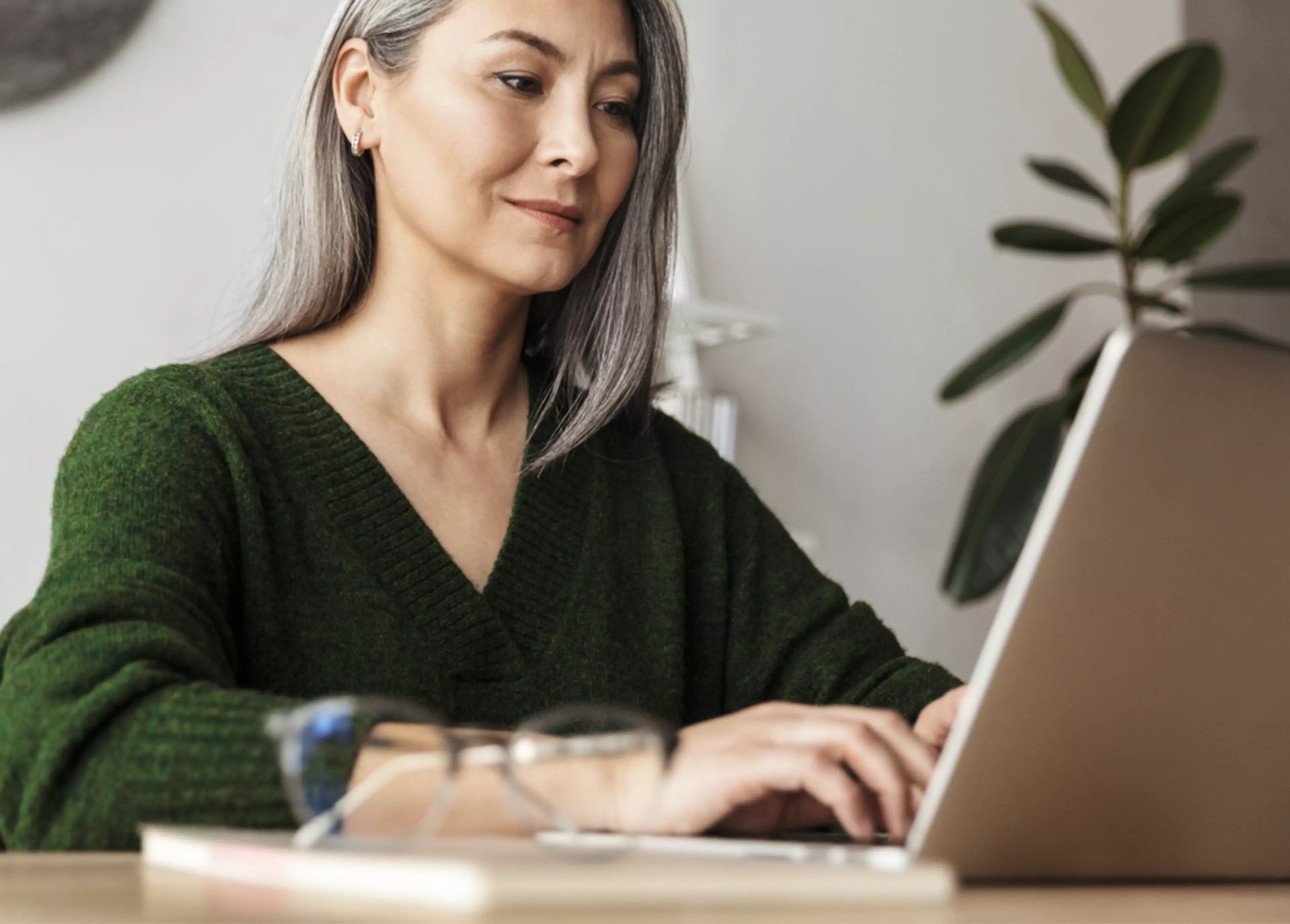 Mature woman sitting behind a desk, working on her laptop.