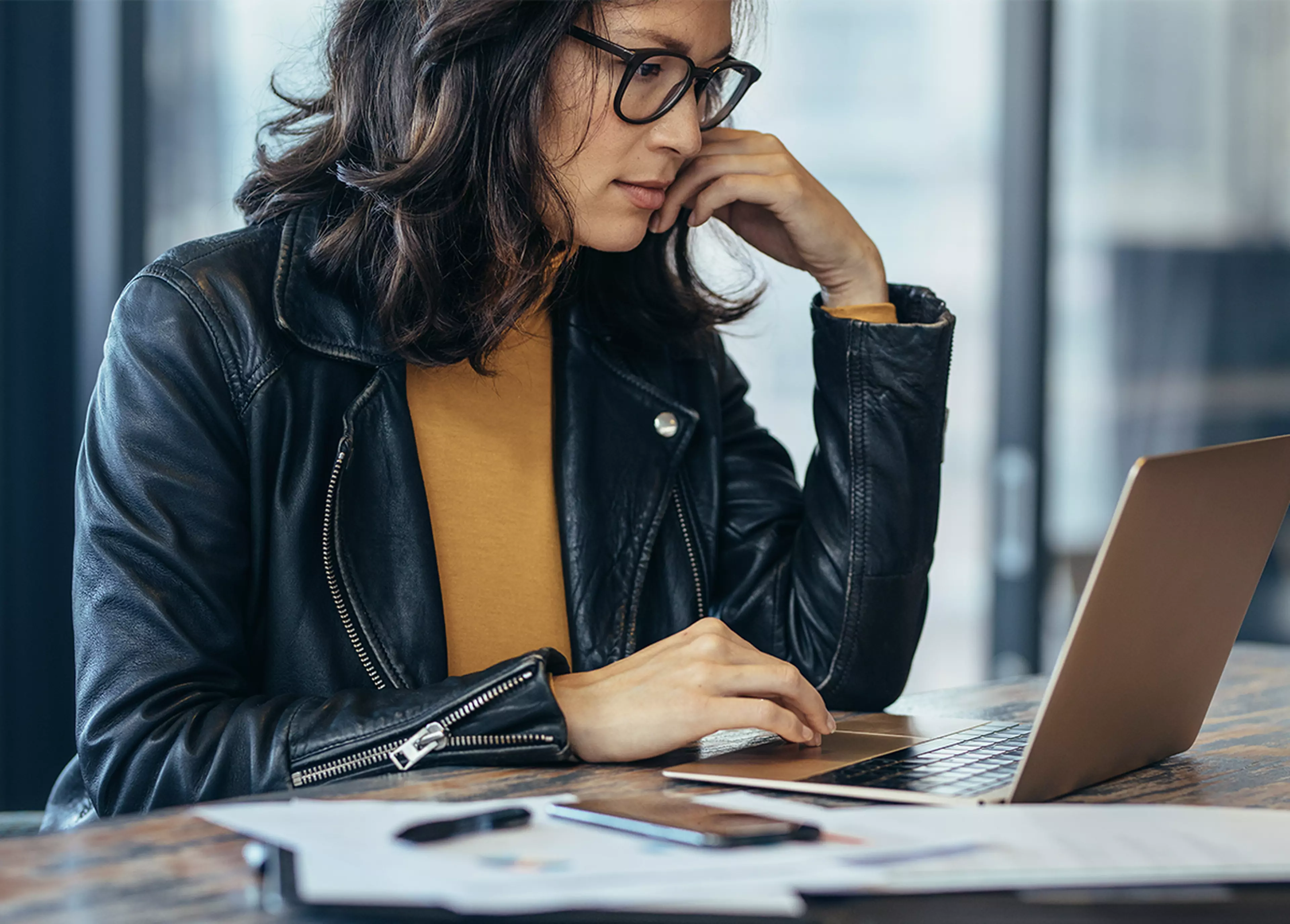 Woman sitting behind a desk, looking at her laptop.