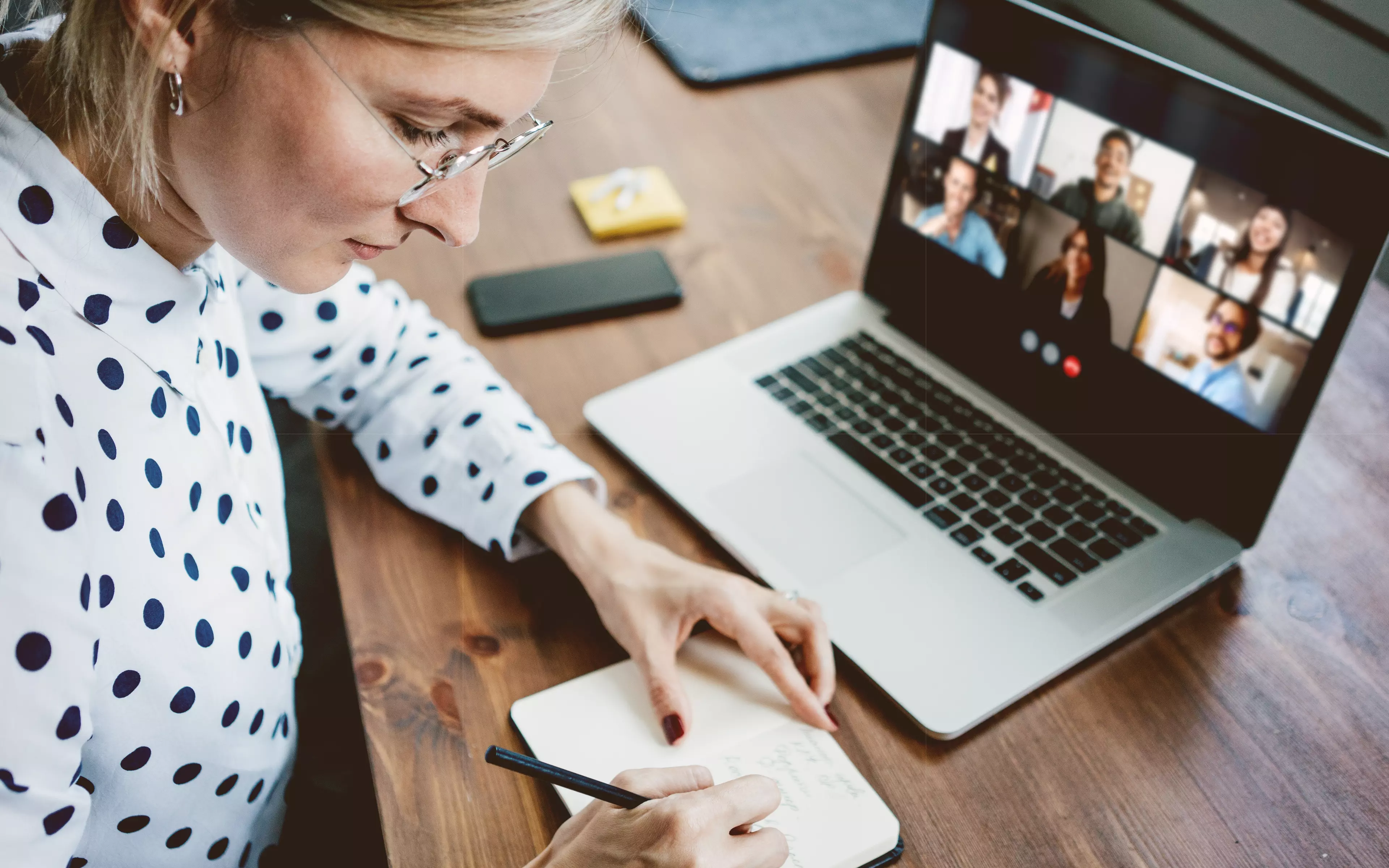 A business woman watching people in the group online call and taking notes