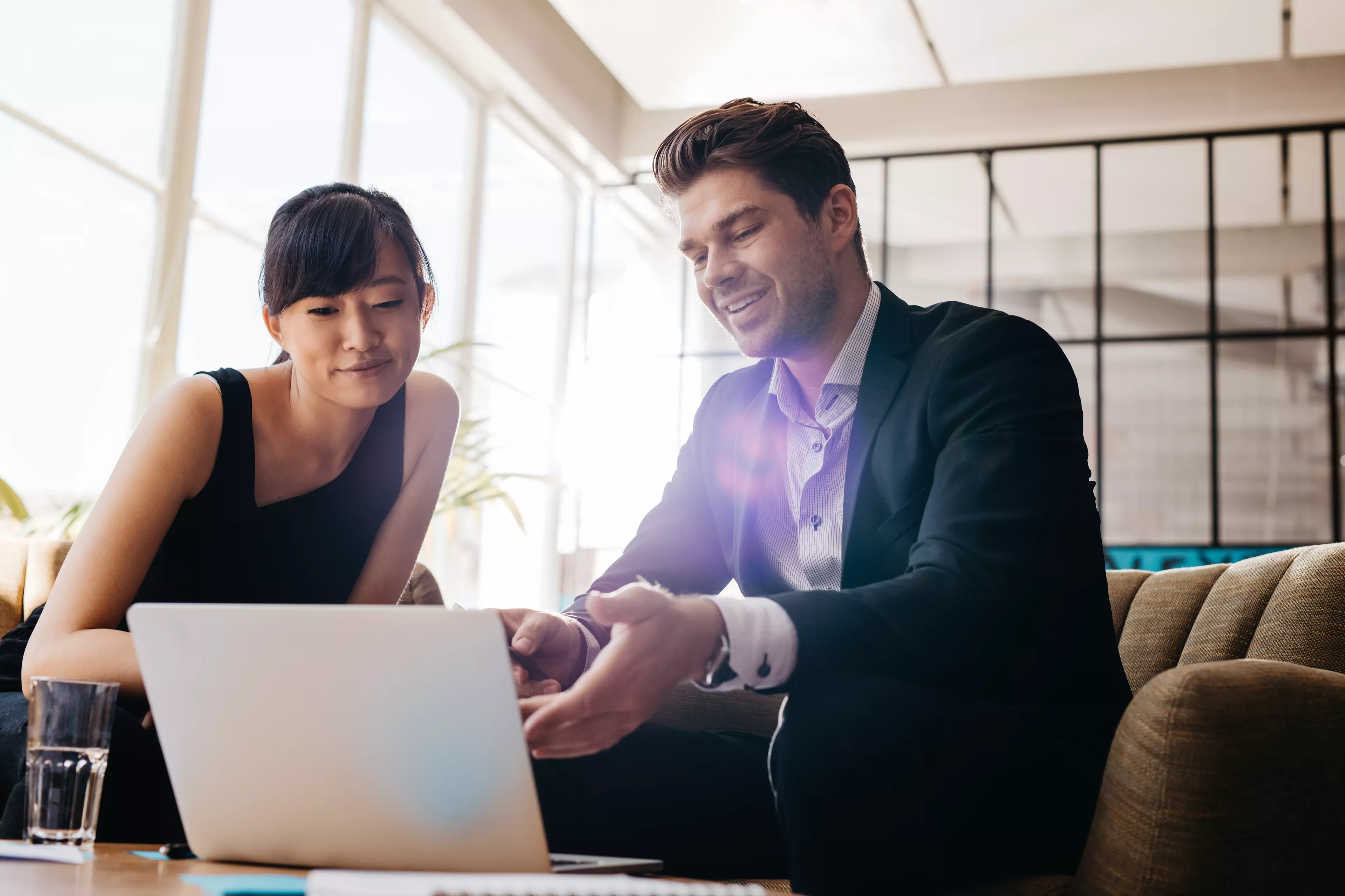  Man and woman sitting, looking at a laptop screen.