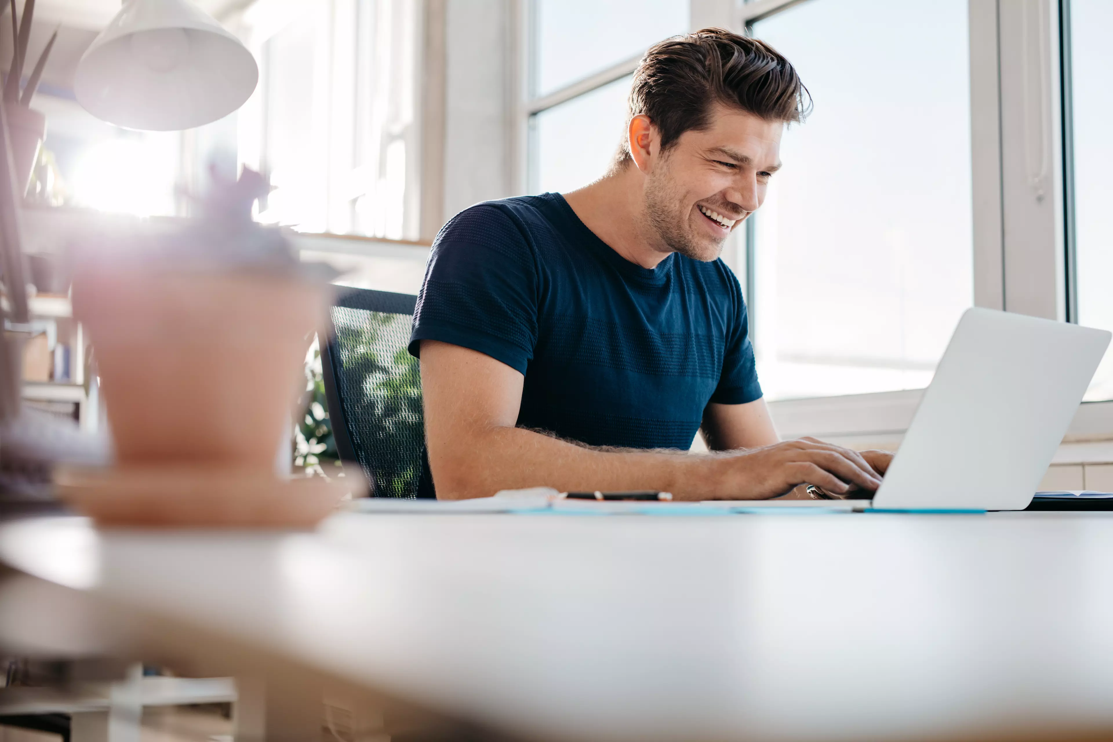 Uśmiechnięty mężczyzna siedzący przed laptopem smiling man sitting in front of a laptop