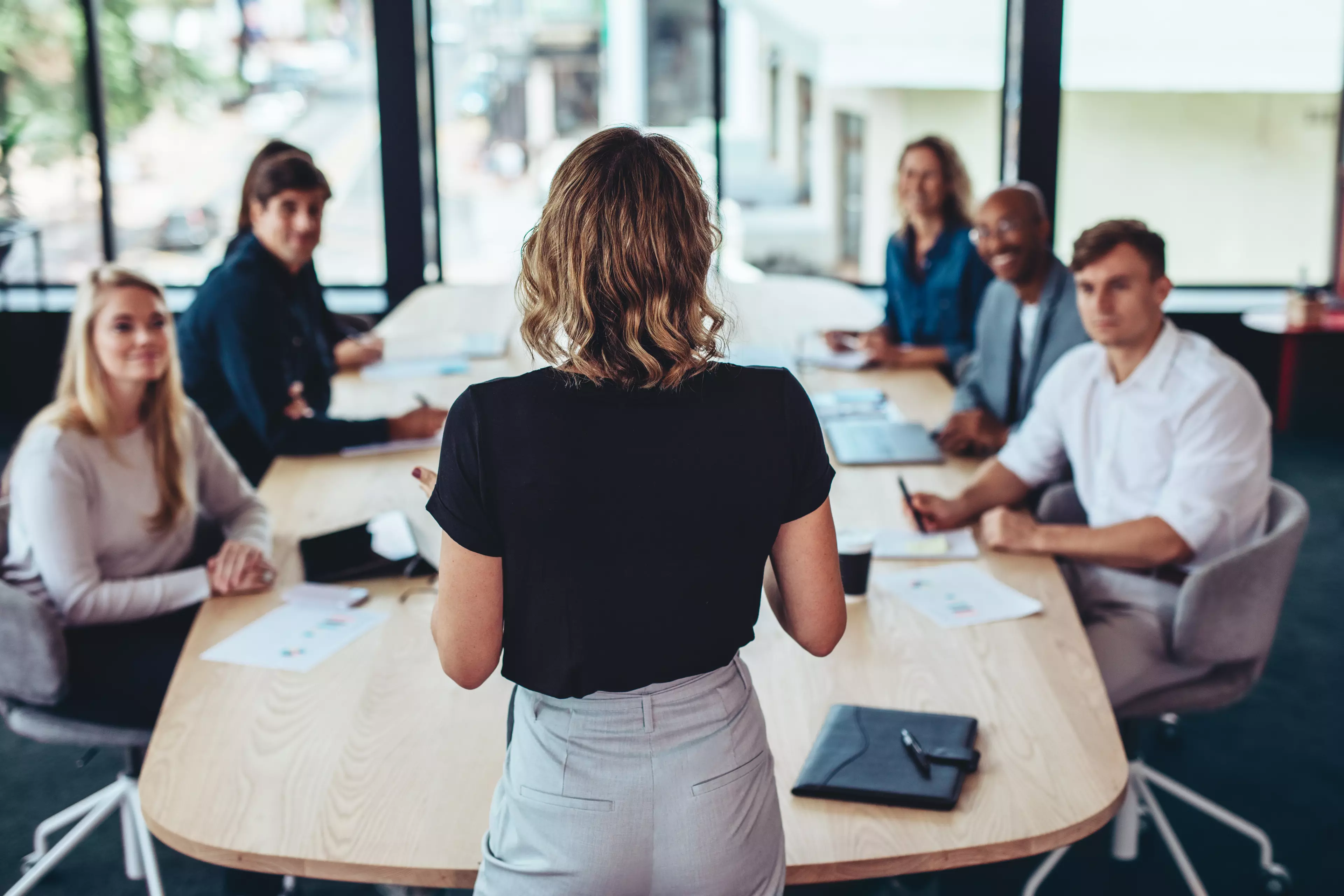 An office meeting of young coworkers seating at a large table.