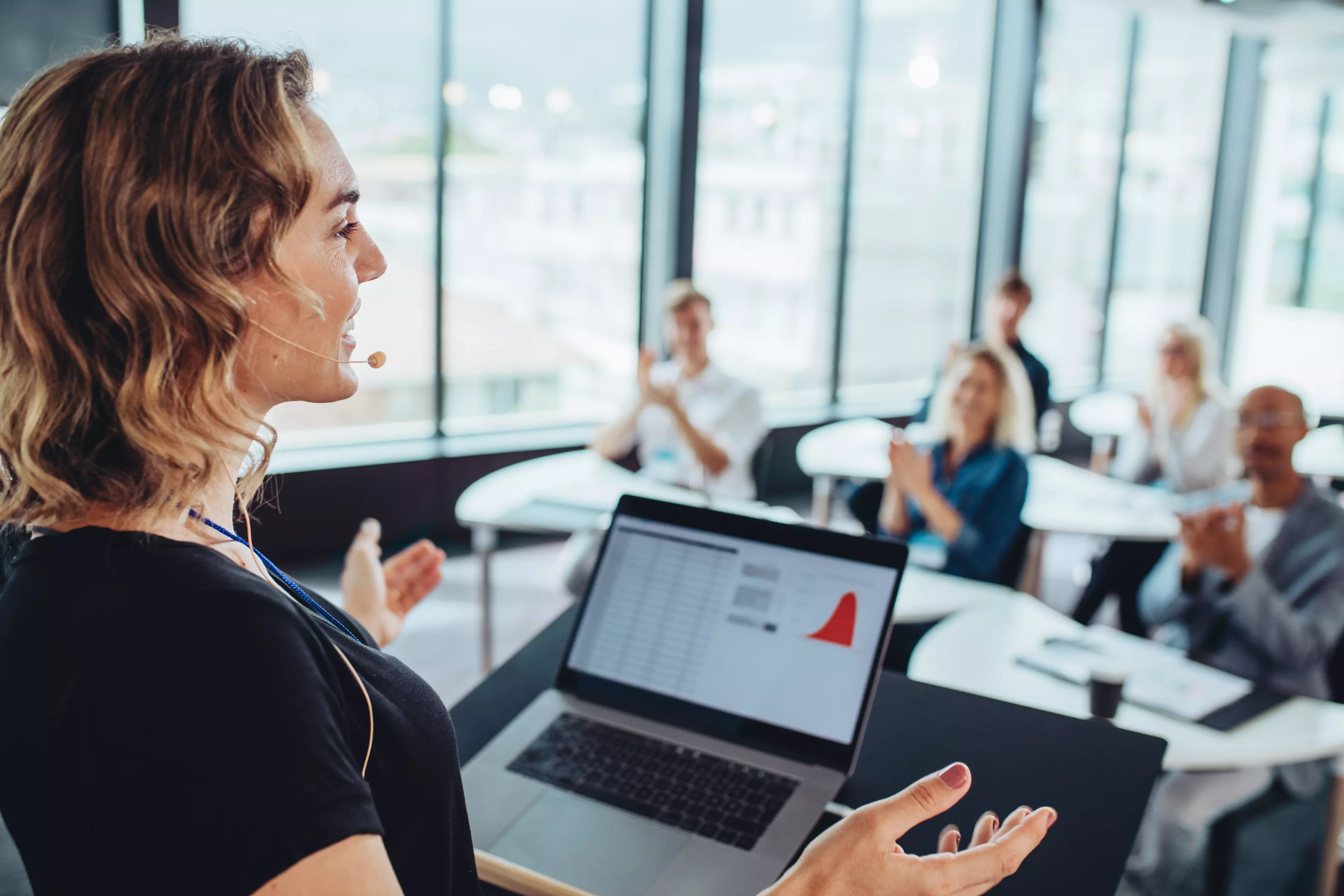  A smiling woman speaks to a team during an office meeting.