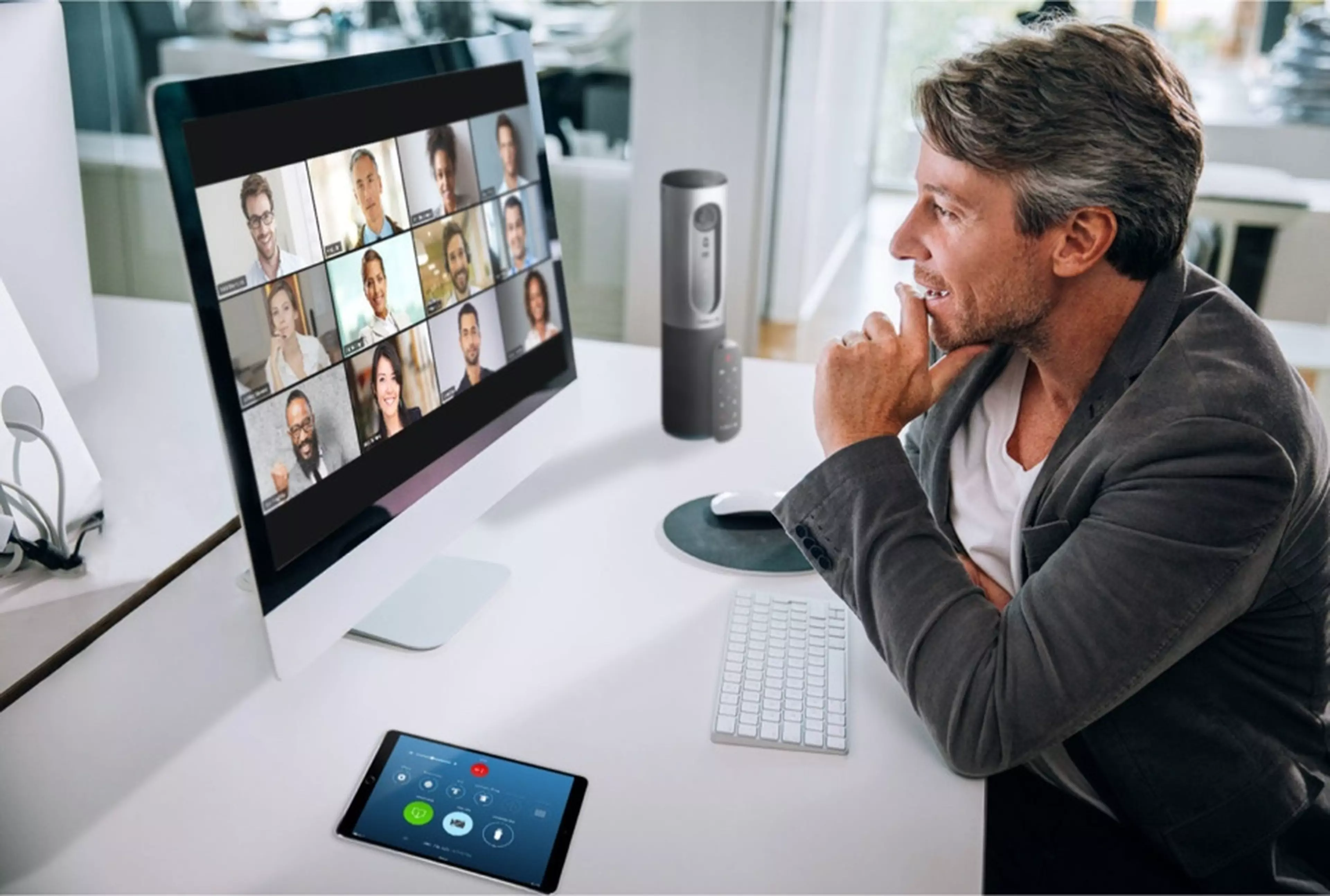 A man talking to a group of people online via a videoconferencing software on a desktop.